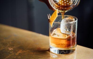 Bartender pouring an old fashioned, glass of whiskey alcohol