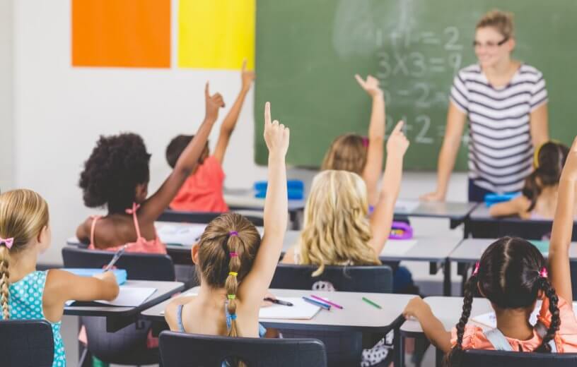 Children raising hands in classroom