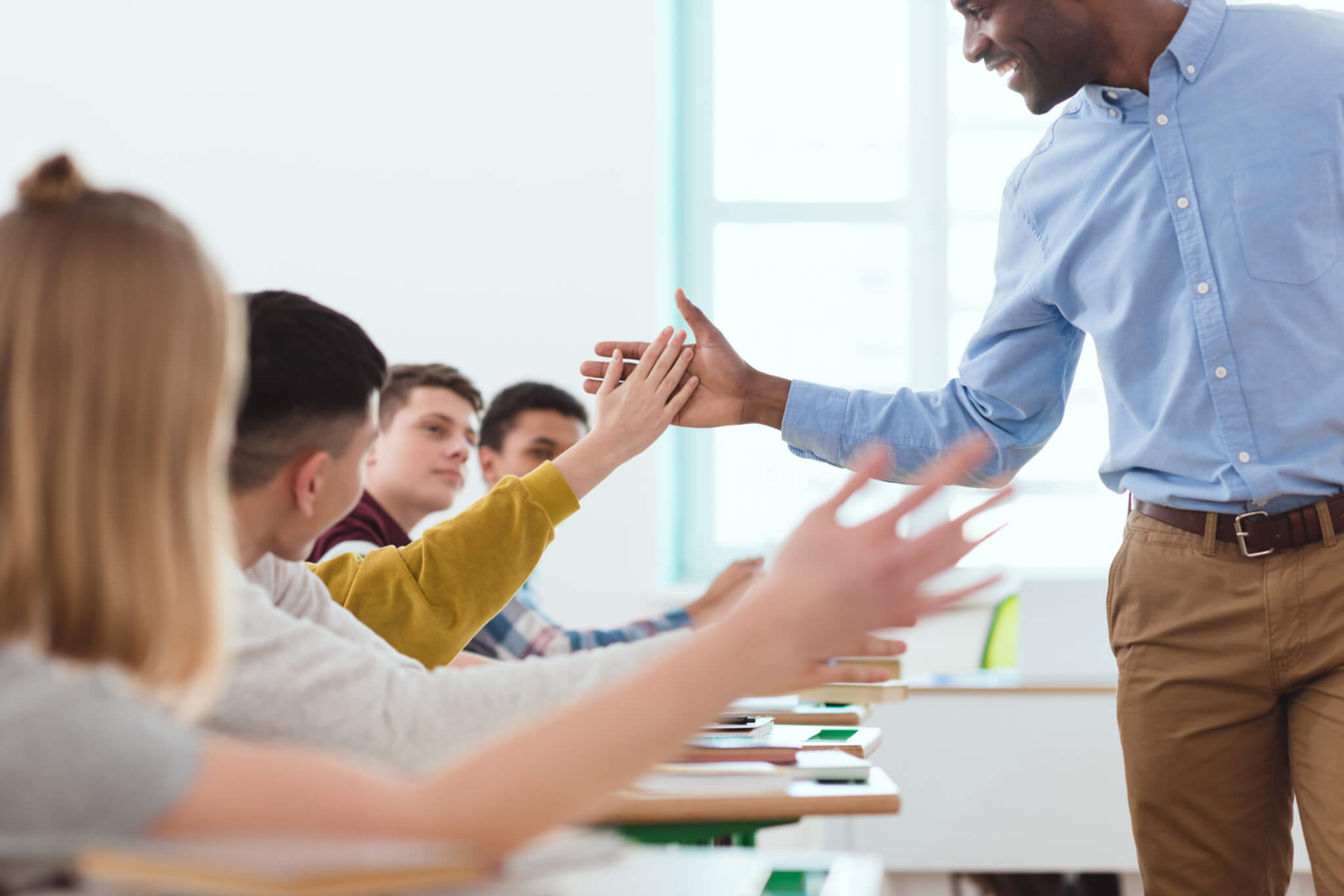 High school teacher high-fiving teen students