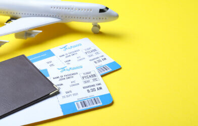 Passport with tickets and toy airplane on yellow background.