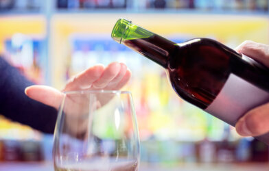 Woman's hand rejecting more alcohol from wine bottle