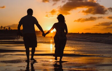 couple standing on body of water during golden hour