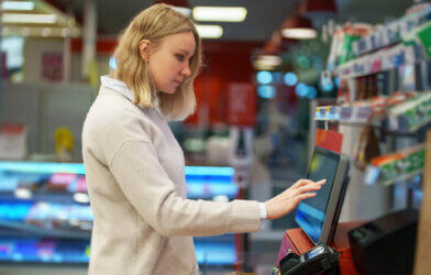 Woman pays at self-checkouts in supermarket.